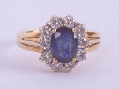 An 18ct yellow gold cluster ring set with a central oval cut sapphire approx. 1.50 carats,