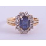 An 18ct yellow gold cluster ring set with a central oval cut sapphire approx. 1.50 carats,