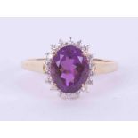 A 9ct yellow gold cluster ring set with an oval cut amethyst, approx. 2.50 carats, surrounded by