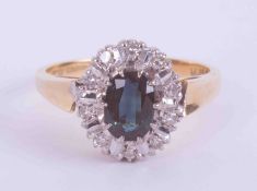 An 18ct yellow & white gold cluster ring set with a central oval cut sapphire, approx. 0.75