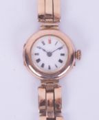 A ladies vintage 9ct gold wristwatch and bracelet, the enamel dial with red twelve, roman