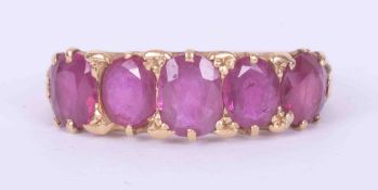 A yellow gold (not hallmarked or tested) ring set with five mixed cushion cut Burmese rubies, the