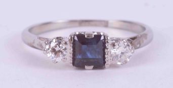 A platinum three stone ring set with a central square cut sapphire, approx. 0.36 carats, with one