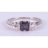 A platinum three stone ring set with a central square cut sapphire, approx. 0.36 carats, with one