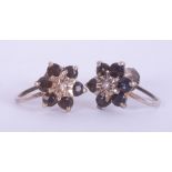 A pair of 9ct white gold flower cluster earrings set with round cut dark blue sapphires and a