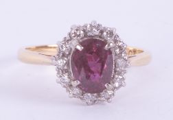 An 18ct yellow gold & platinum cluster ring set with a central oval cut ruby, approx. 0.99 carats,