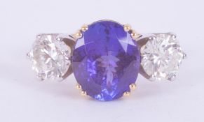 An impressive 18ct yellow & white gold three stone ring set with an oval cut tanzanite, approx. 3.95