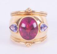 An 18ct yellow gold designer ring by Theo Fennell, set with a central oval cabochon & faceted cut