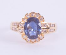 An 18ct yellow gold cluster style ring set with a central oval cut sapphire, approx. 1.18 carats,