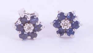 A pair of 9ct white gold flower cluster studs set with small round sapphires & a small central round