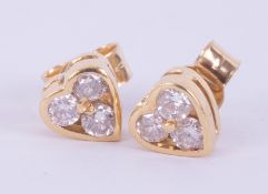 A pair of 18ct yellow gold heart shaped studs set with three round brilliant cut diamonds, total