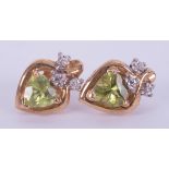 A pair of 9ct yellow gold earrings set with a heart shaped peridot and one tiny diamond above, the