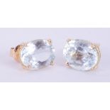 A pair of 14k yellow gold stud earrings set with oval cut aquamarines measuring 10mm x 8.2mm x 6.