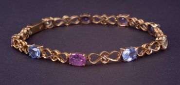 A fancy 18ct yellow gold bracelet set with oval cut multi-coloured sapphires, interspaced with a