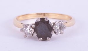 An 18ct yellow gold & platinum three stone ring set with a central oval cut dark blue sapphire,