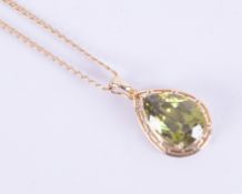 A yellow gold pendant (not hallmarked or tested) set with a multi-faceted pear shaped peridot