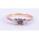 An 18ct yellow & white gold three stone ring set with a central round cut dark blue sapphire with