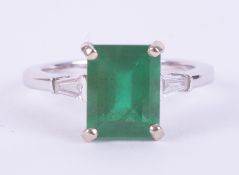 An 18k white gold ring set with a central emerald cut emerald approx. 2.95 carats with a tapered