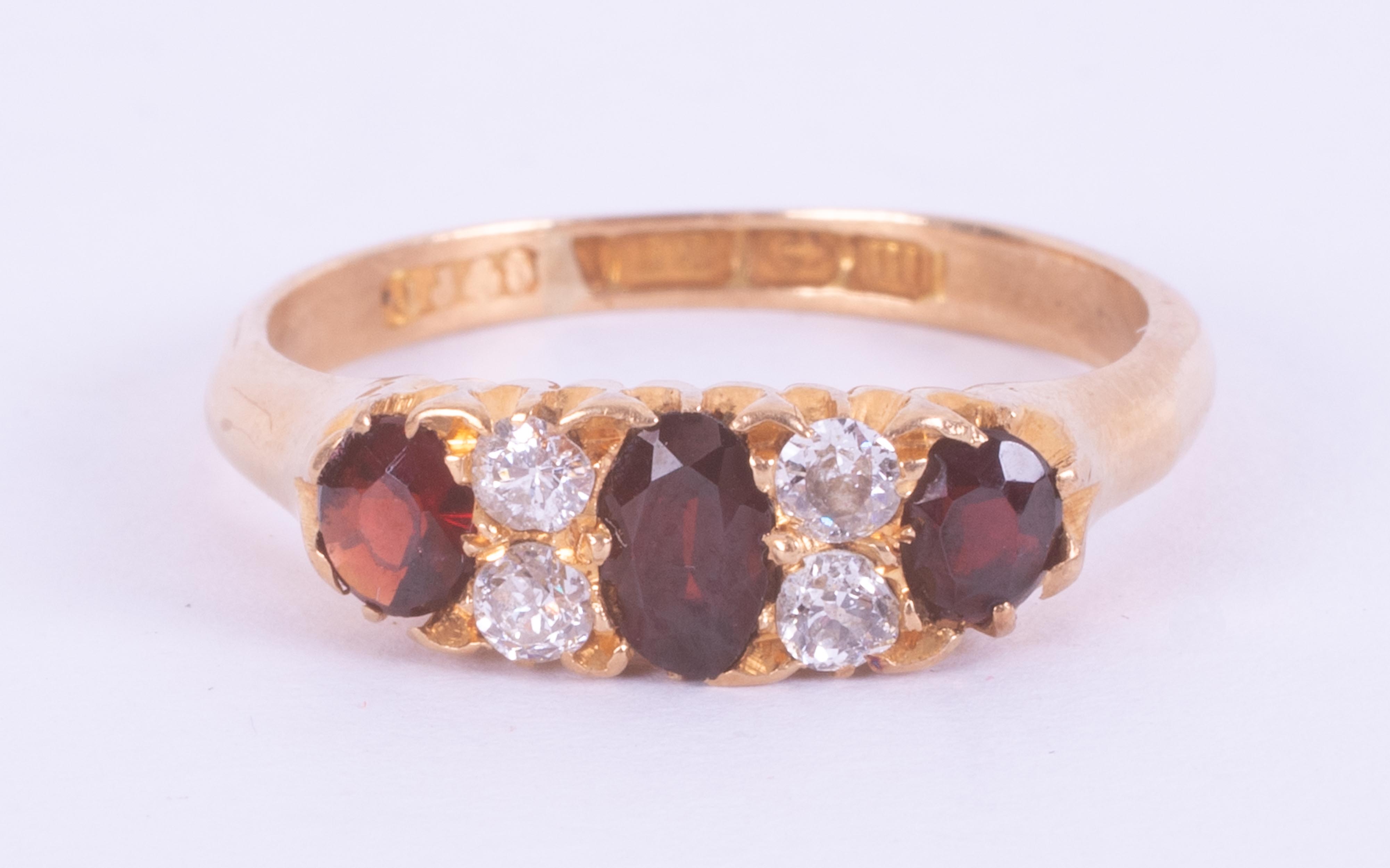 An 18ct yellow gold ring set with three oval cut garnets interspaced with four old round cut