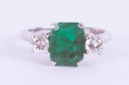 An 18ct white gold three stone ring set with a central emerald cut emerald, approx. 1.95 carats with