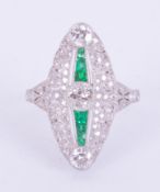 A fine platinum Art Deco style marquise shaped ring set with a line of emeralds in slightly