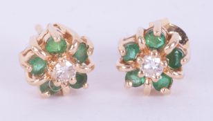 A pair of 14k yellow gold flower cluster earrings set with a central round cut diamond and