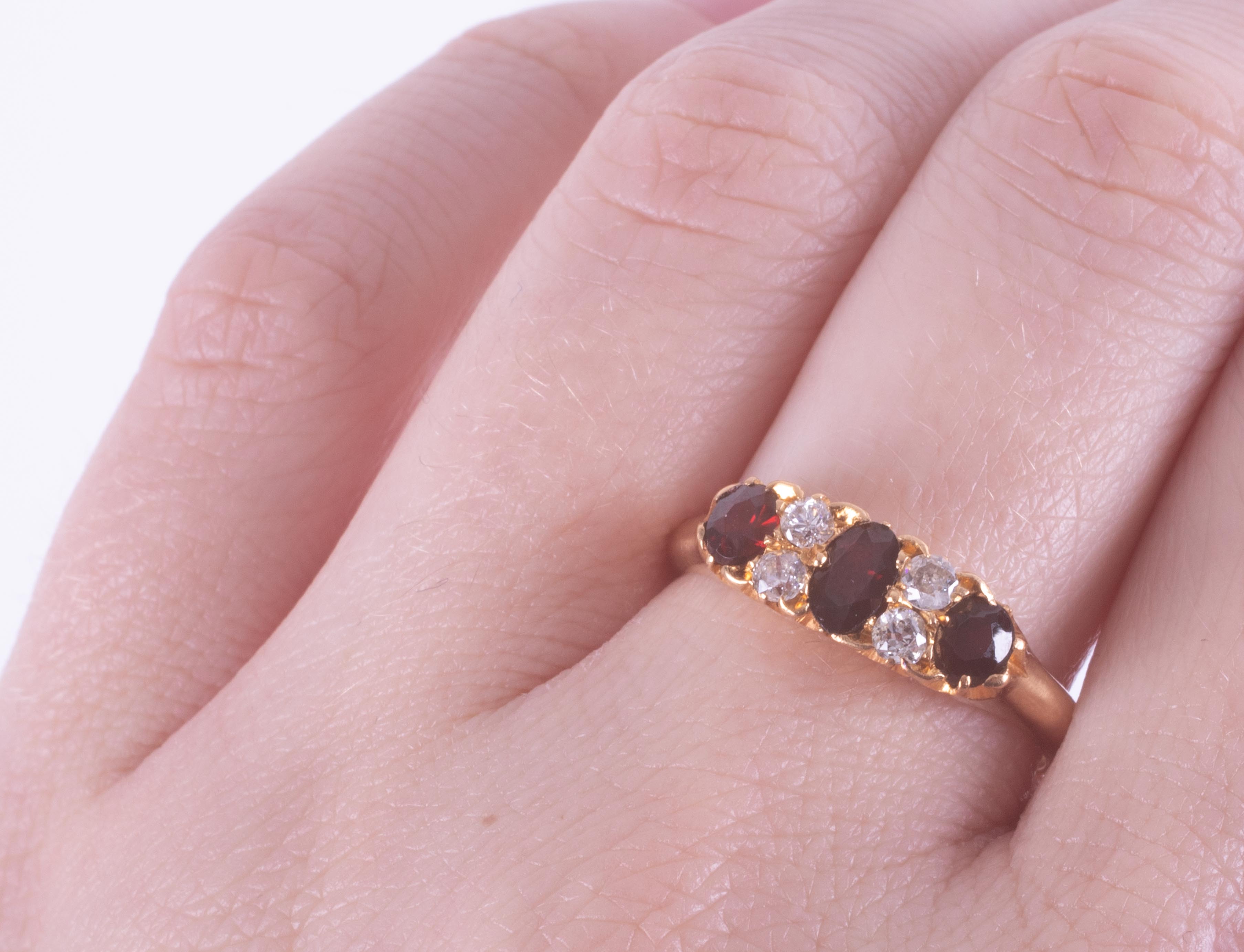 An 18ct yellow gold ring set with three oval cut garnets interspaced with four old round cut - Image 2 of 2