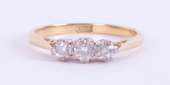An 18ct yellow & white gold three stone ring set with three small round cut diamonds, total weight