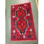 RED GROUND PATTERNED BALUCHI RUG WITH LARGE CENTRAL MEDALLION (142 X 85 CM)
