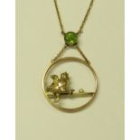 YELLOW METAL HOOP PENDANT SUSPENDED FROM A SET GREEN STONE (PERHAPS PERIDOT), MODELLED WITH A