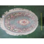 PALE GREEN GROUND FLORAL PATTERNED EMBOSSED OVAL RUG WITH TASSELED EDGE.
