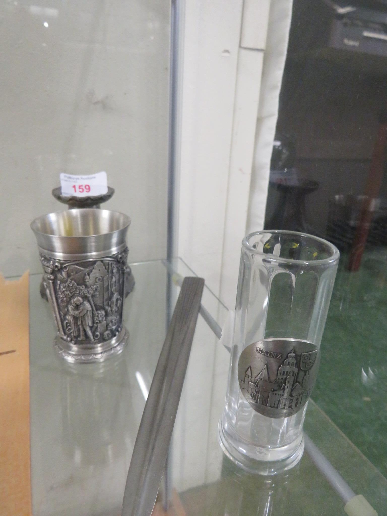 A pewter candlestick, a pewter beaker, a pewter letter opener and drinking glass with pewter plaque