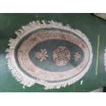 PALE GREEN ROUND EMBOSSED OVAL FLOOR RUG WITH TASSELED EDGE.