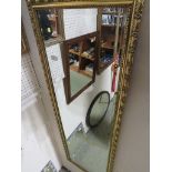 Long rectangular bevelled edge mirror in gold coloured frame.