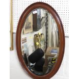OVAL BEVELLED EDGE WALL MIRROR IN MAHOGANY FRAME.