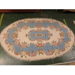 CREAM AND BLUE GROUND FOLIATE PATTERN OVAL RUG.