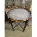 MIDDLE EASTERN STYLE ENGRAVED BRASS TRAY TABLE ON FOLDING WOODEN STAND.