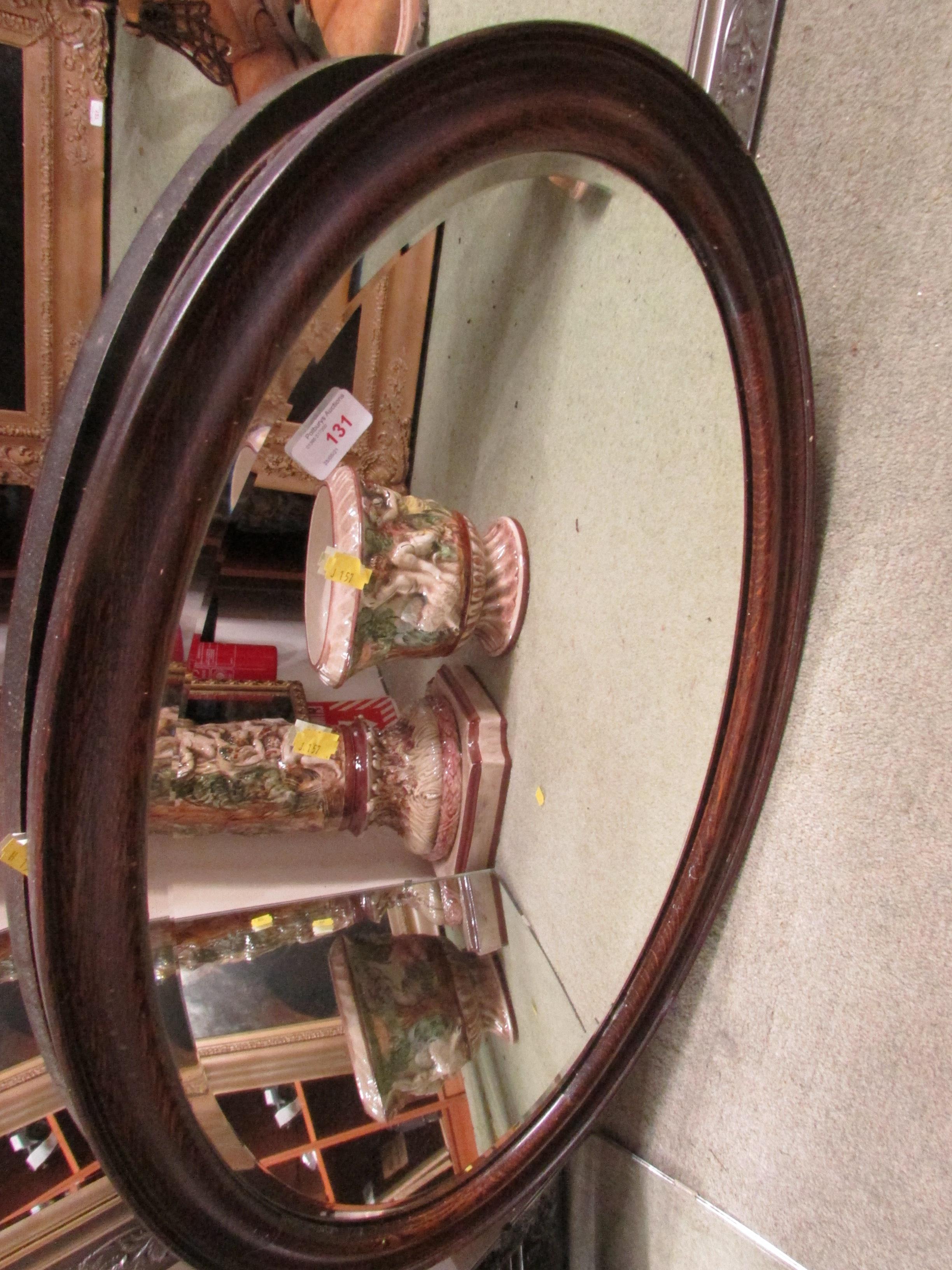 OVAL BEVELLED EDGED WALL MIRROR IN AN OAK FRAME.