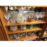 FOUR SHELVES OF GLASS WARE INCLUDING STEM DRINKING GLASSES , BOWLS, AND VASES.