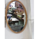 OVAL BEVEL EDGED MIRROR IN A OAK FRAME.