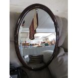 OVAL BEVEL EDGED MIRROR IN A VARNISHED FRAME.