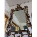 RECTANGULAR WALL MIRROR IN A HEAVILY MOULDED SCROLLED GILT EFFECT FRAME.