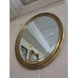 OVAL BEVEL EDGE MIRROR IN A GILT FRAME.