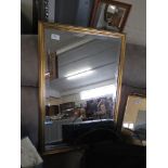 RECTANGULAR BEVEL EDGED WALL MIRROR IN A GILT EFFECT FRAME.