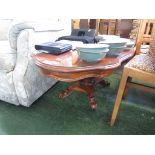 A SHAPED OVAL COFFEE TABLE WITH INLAID TOP AND GLASS COVER ON FOUR SCROLLED FEET.