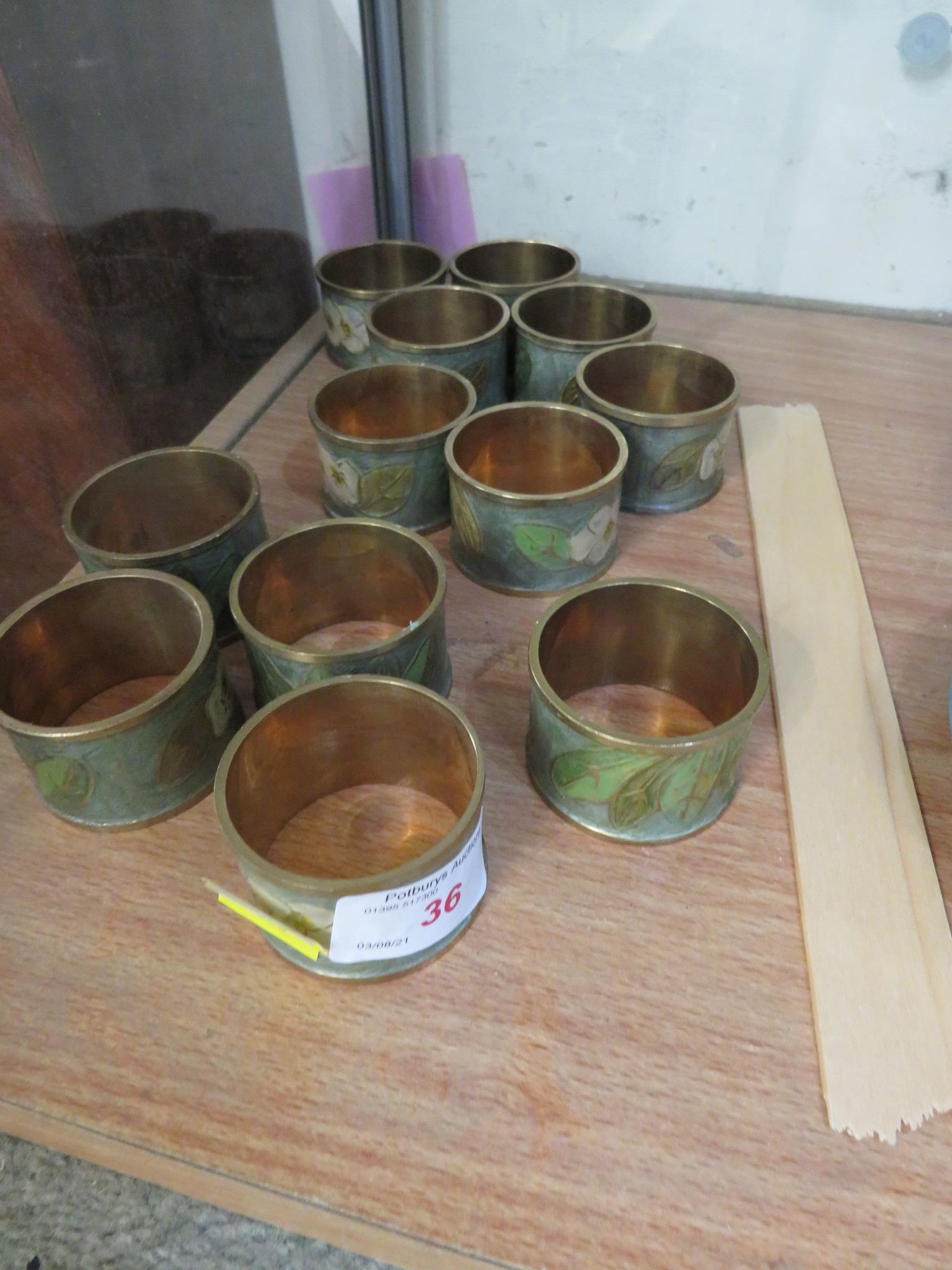 TWELVE ENAMELLED BRASS NAPKIN RINGS.