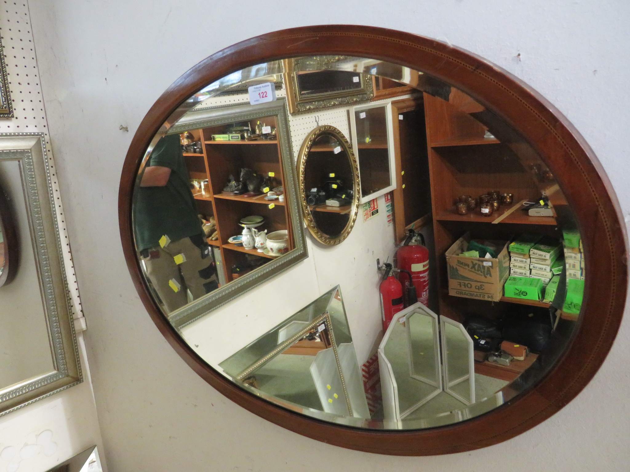 OVAL BEVEL EDGED MIRROR IN A BANDED MAHOGANY EFFECT FRAME.