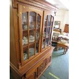 AN ILLUMINATED MID WOOD GLAZED DRESSER WITH TWO DOORS TO TOP, THE BASE WITH TWO CUTLERY DRAWERS