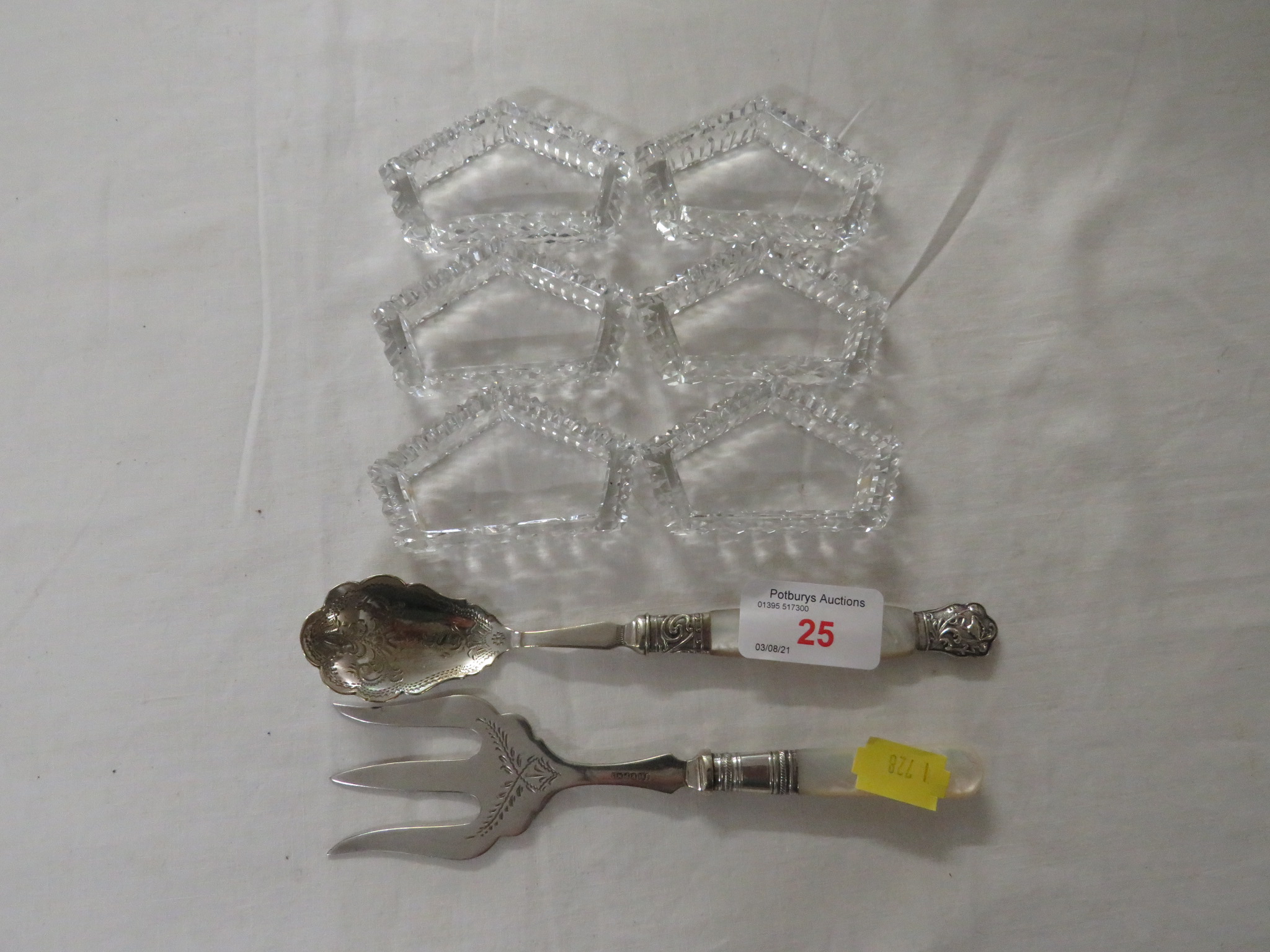 SIX CUT GLASS NAPKIN RINGS, SILVER-PLATED FORK AND SPOON WITH MOTHER OF PEARL HANDLES.