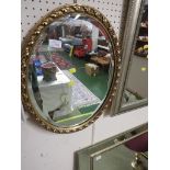 OVAL BEVEL EDGED MIRROR IN A GILT EFFECT FRAME.